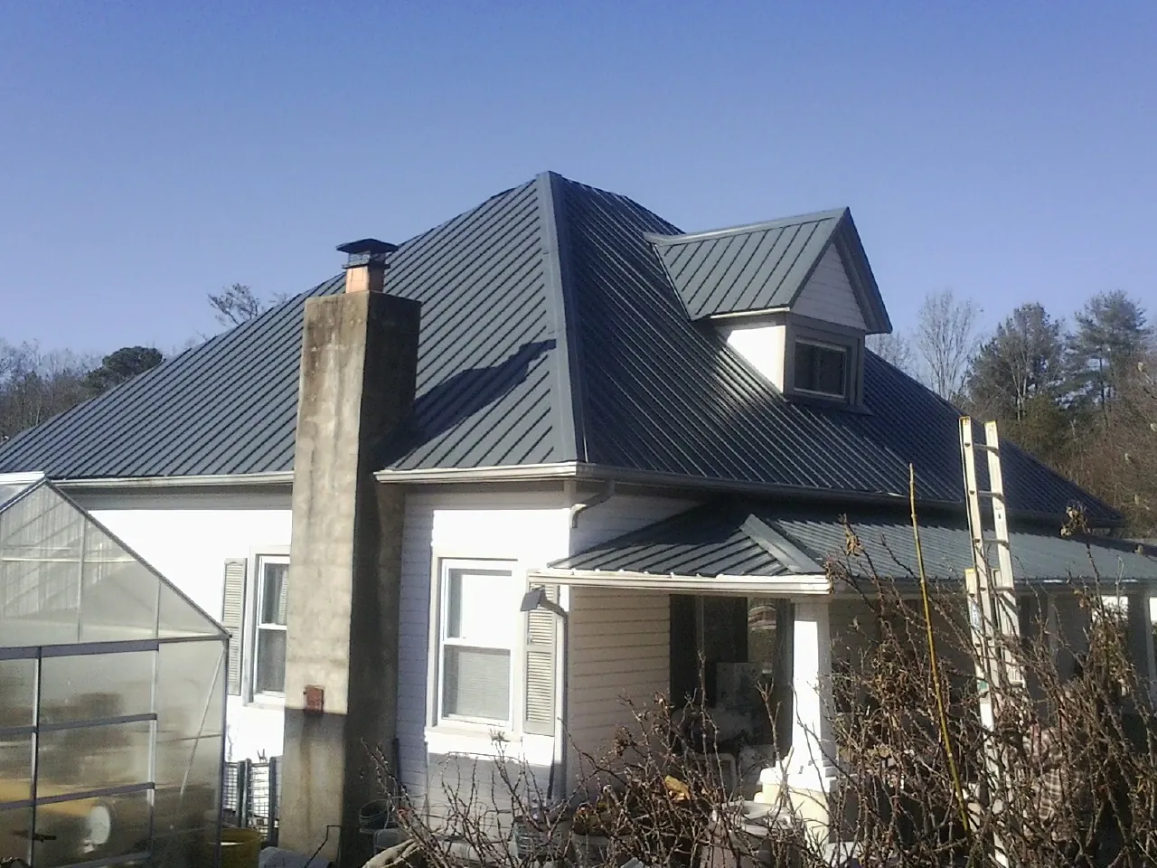 Dark blue standing seam metal roof on a white farmhouse with dormer — Slate & Tile Roof Repair by Roofing Brothers in Tyrone
