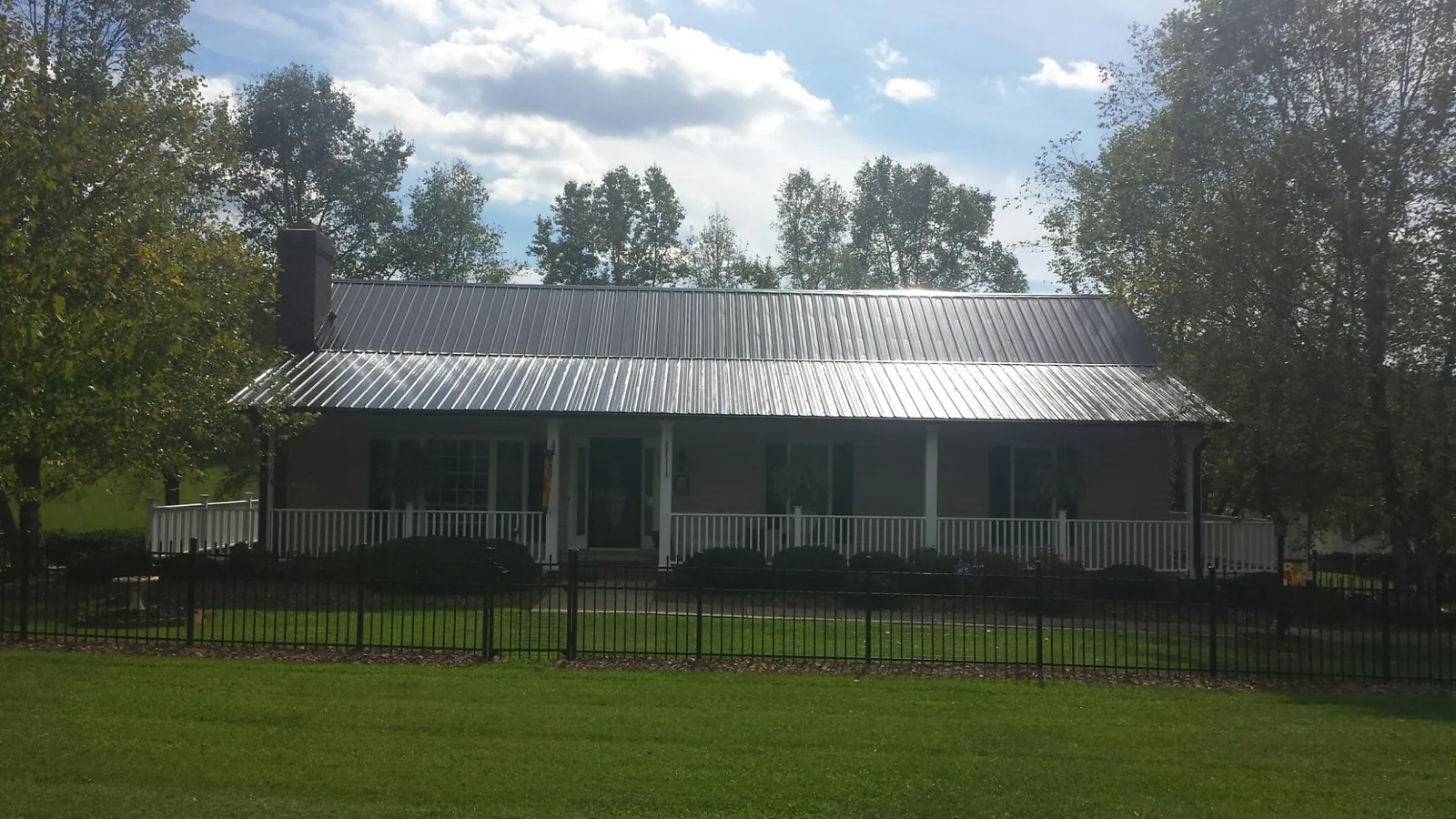 Gray metal roof on a brick ranch with a full width front porch — Gutter Guard Installation work by our crew in Tyrone